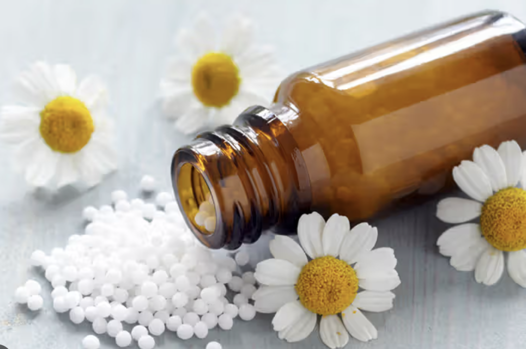 Homeopathic remedy — amber bottle with white globules and chamomile flowers
